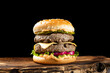 Double cheeseburger with cutlet on wooden board and black background