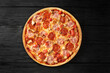 Apetite pizza on a black wooden background top view with sausage and meat