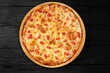 Apetite pizza on a black wooden background top view with sausage and meat