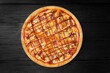 Petite pizza top view on black wooden background