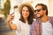 © opolja - Loving cheerful happy couple taking selfie in the city.