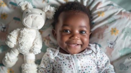 Wall Mural - A joyful baby with a big smile lying on a patterned blanket next to a white stuffed animal.