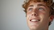 A close-up of a young man with curly hair blue eyes and a radiant smile looking upward with a sense of wonder or joy.