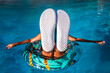 A teenager girl relaxes on a pool ring, her sneaker soles upturned towards the camera, ready for an overlay of text. Leisure, youth, and fun in the sun.