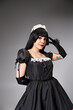 © LIGHTFIELD STUDIOS - attractive woman cosplaying sexy maid with black gloves showing peace gesture and looking at camera