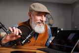 Fototapeta  - Studio podcast avec un micro et un ordinateur tablette et un homme souriant au look stylé et vintage avec une barbe hipster