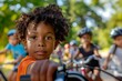 Smiling, joyful african american child rides a bicycle in the park, with other children on bikes in the background. Happy and active childhood, outdoor fun.