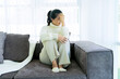 Woman spend time at home seated on sofa