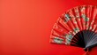 A traditional red folding fan with floral design on a solid background.