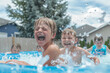 Children Splashing Water in Outdoor Pool
