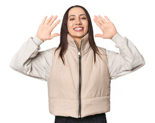 Modern young Caucasian woman portrait on studio background showing number ten with hands.