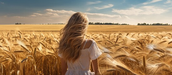 Wall Mural - A happy woman in a white dress is standing in a field of wheat under the clear blue sky, surrounded by the natural landscape of grasslands and distant horizon