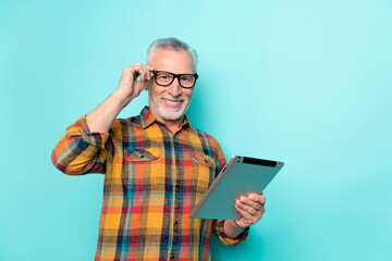 Poster - Photo of positive man pensioner dressed checkered shirt glasses holding device empty space isolated teal color background