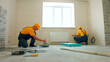 © DenisProduction.com - Priming floor in a large house. Workers insulated floor.