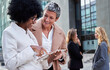 © Gigi Delgado - Multiracial mature businesswomen discussing cheerfully the new project ideas together, using the work digital tablet, standing outside financial district. Copy space.