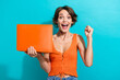 Portrait of overjoyed girl wear orange knit top holding laptop win betting scream yes clenching fist isolated on blue color background