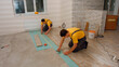 © DenisProduction.com - Workers lay the floor in the house. Laying laminate.