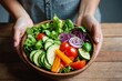 Hand of woman holding salad bowl with fresh vegetables - healthy eating concept. Bowl is filled with a variety of colorful vegetables, making it a healthy and nutritious meal