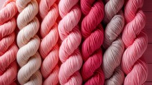   Several Skeins Of Yarn In Pink, Red, And White On A Pink Background