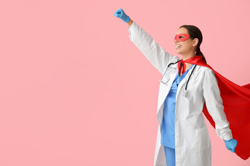 Poster - Young female doctor in superhero costume on pink background