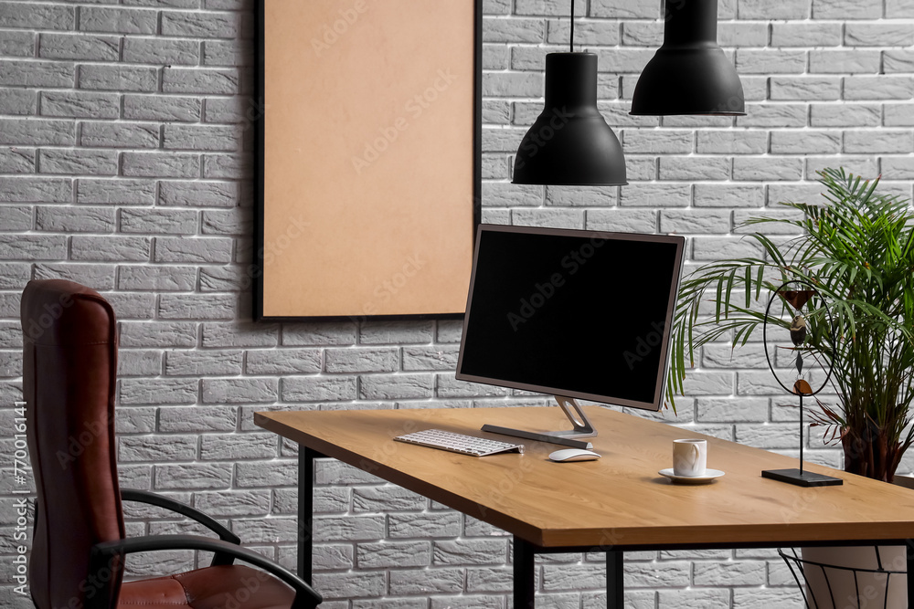 Stylish workplace with modern monitor near brick wall