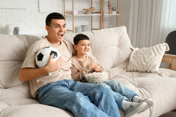 Canvas Print - Happy father with his little son watching football game at home