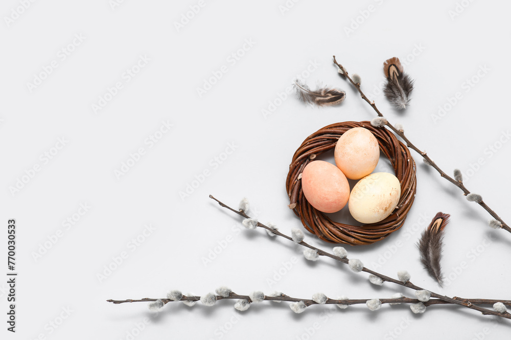 Painted Easter eggs in nest with pussy willow branches on white background