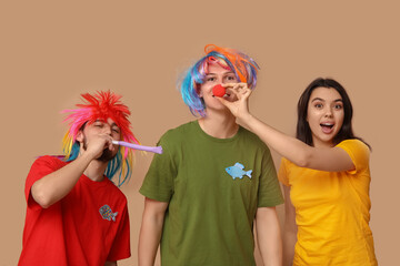 Wall Mural - Young friends in funny disguise with whistle on brown background. April fool's day celebration