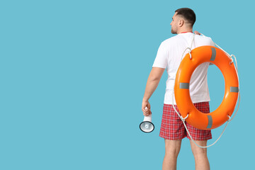 Wall Mural - Young lifeguard with lifebuoy and megaphone on blue background