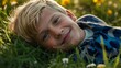 © Geenius Stock - Portrait d'un enfant heureux couché dans l'herbe entouré de fleurs dans une prairie, zen, relax, sourire