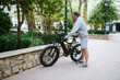 © Taras Grebinets - Full length of young man renting an electric bike for riding in the city. Electric bicycle - public eco transport