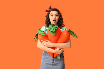 Wall Mural - Emotional pin-up woman holding toy carrots on orange background