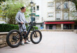 © Taras Grebinets - Young man in sports wear, renting and riding e-bikes in the city. Bike sharing city service