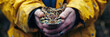 A close view of a person in a yellow jacket gently cradling a python in their hands