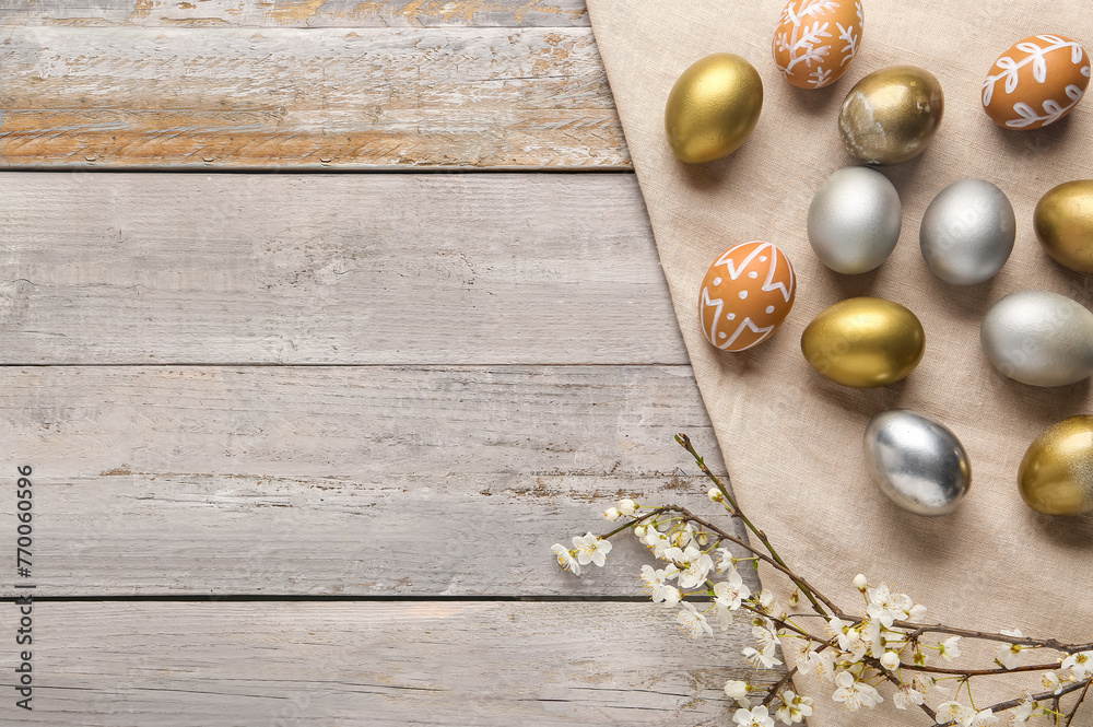 Easter eggs and blooming branches on grey wooden background. Top view