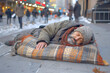 Homeless man on city street. Old sad man sleeping on cardboard in torn clothes seeking help, hungry poor person concept