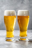 Fototapeta  - Dwie szklanki złocistego piwa z pianką