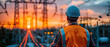 An electrician in hardhat, ensuring safety observes a high-voltage power line installation against the backdrop of a vibrant sunset