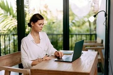 Poster - Happy woman working on her laptop at her home office The cozy and stylish workspace showcases her modern technology and entrepreneurial spirit With a cup of coffee nearby, she types away, fully