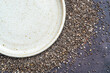 Chia seeds (Salvia hispanica) Salba chia edible seeds with empty white ceramic plate.