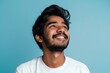 © Marina Shvedak - Happy joyful smiling young indian man looking a side up isolated on light blue background