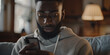 a close up shot of an African American man with short hair and beard wearing a sweatshirt looking at his phone in the living room, generative AI