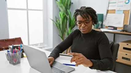 Canvas Print - African american woman with dreadlocks using a computer in modern office setting.