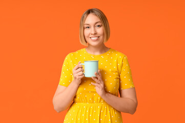 Happy adult woman with cup of coffee on orange background