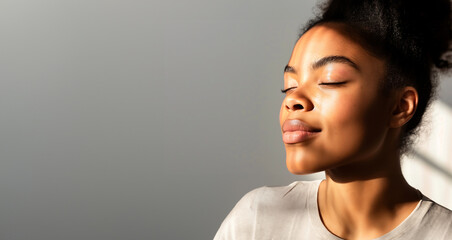 a beautiful african woman with closed eyes is enjoying the sunlight on her face, copy space for text