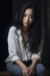 © vefimov - A woman with long black hair is sitting on a wooden bench. She is wearing a white shirt and blue jeans. Scene is sad and contemplative