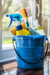 A blue bucket filled with house cleaning products on a hardwood floor at home
