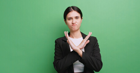 Young businesswoman is denying and disagreeing with something. Isolated on green background in studio.