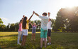 © Studio Romantic - Group of a kids friends playing outside in the park standing in a circle and holding hands up. Happy children playing games and having fun outdoor on a sunny summer day in casual clothes.