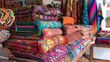 A colorful display of stacked handmade textiles featuring ethnic patterns and intricate designs